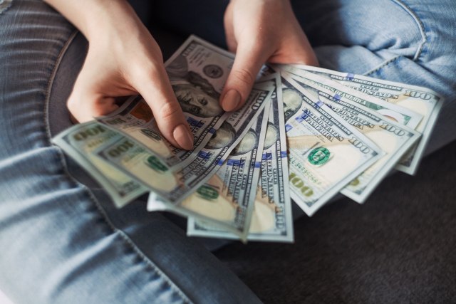 Woman showing her savings with many $100 dollar bills