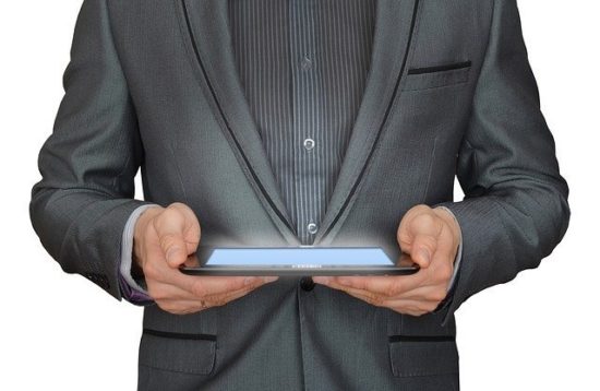 Business man in grey suit holding a tablet with a glowing screen